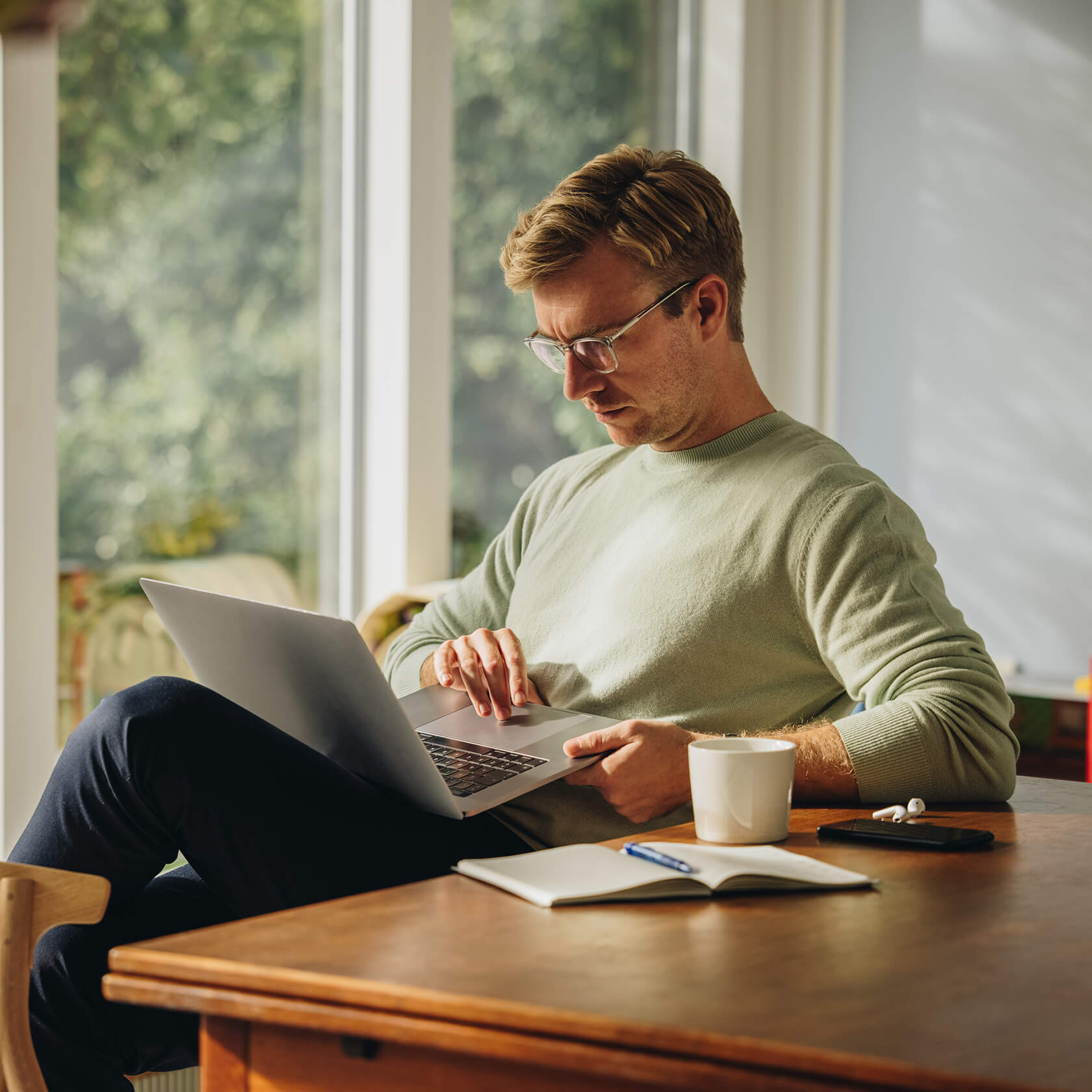 Man using laptop at desk with coffee.